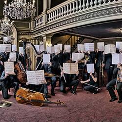 image du musiciens de l'orchetsre visages cachés par une partition ouverte